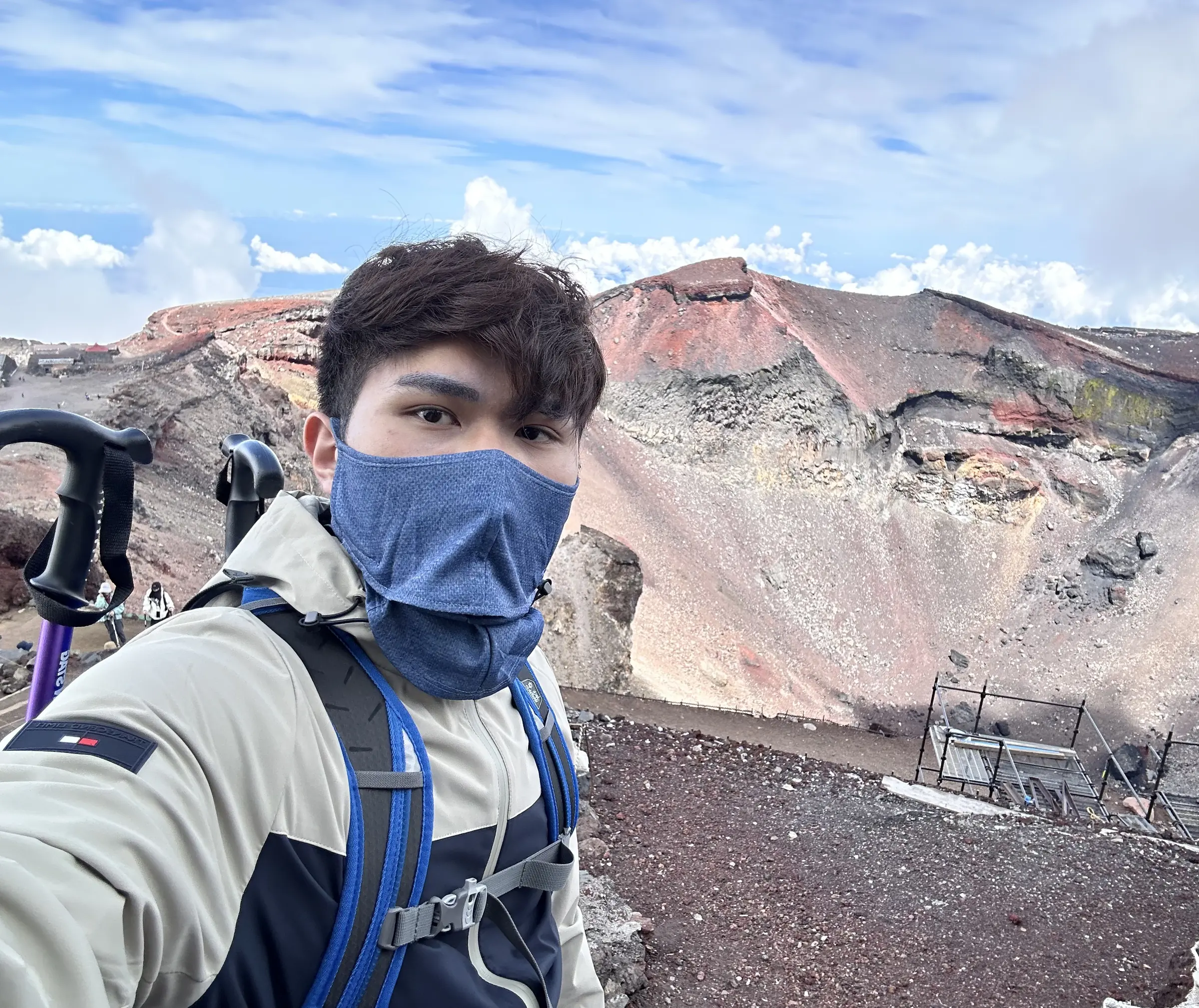 Zuchen on the rim of Mount Fuji's summit crater, red volcanic walls and a sea of clouds behind