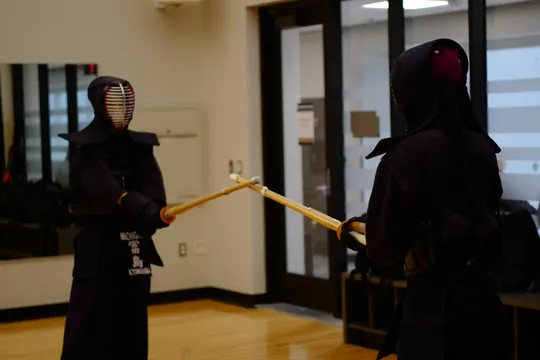 Two club members in kendo armor facing each other with bamboo swords raised