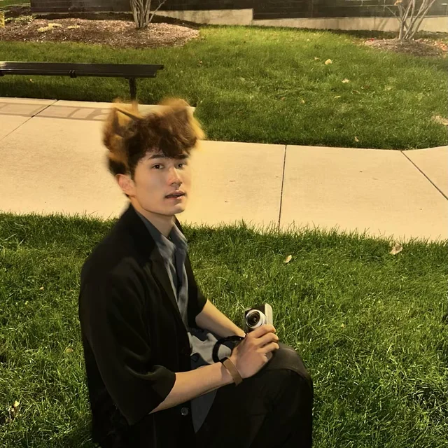 Zuchen Li on the grass at night, holding a camera